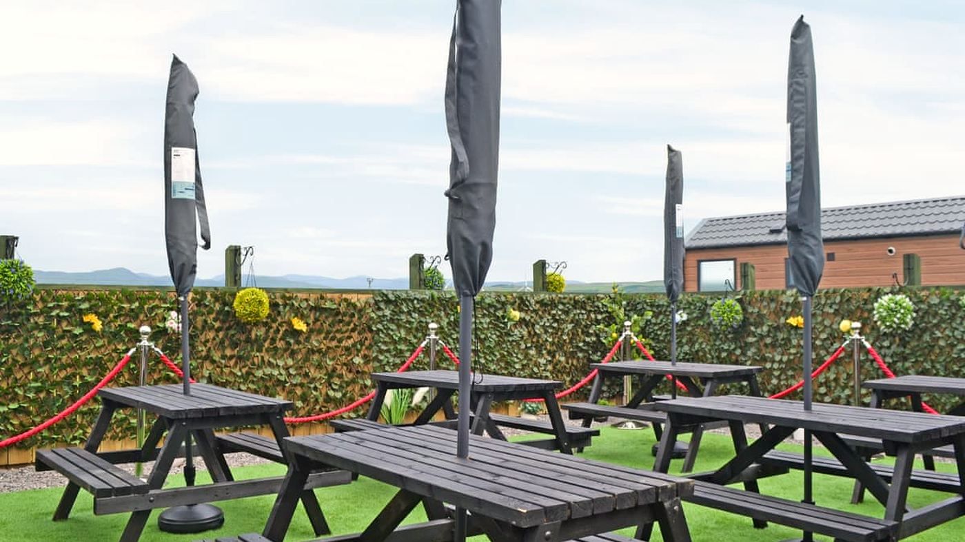 Oily's beer garden — black picnic benches under umbrellas with the Lakeland fells on the horizon