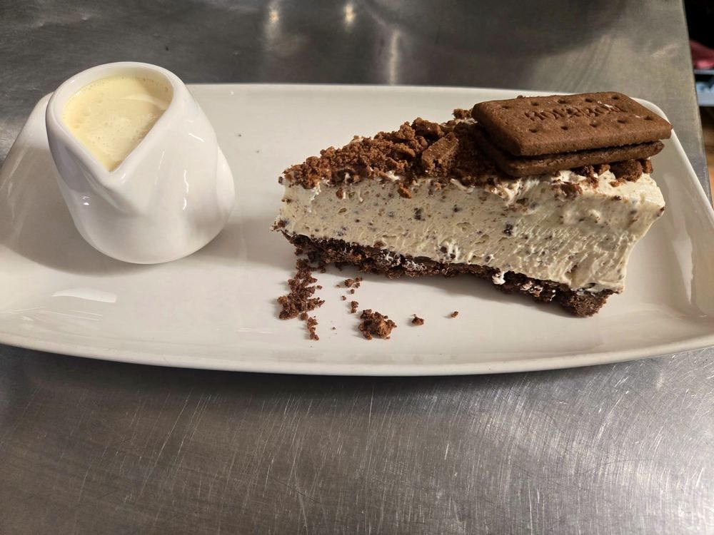 A slice of homemade cheesecake with a jug of pouring cream