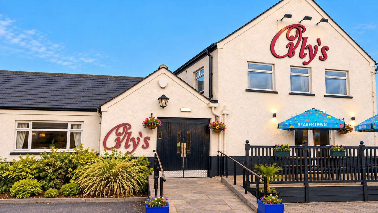 Oily's at Winscales — white rendered pub with red Oily's signage, black doors and terrace under a blue sky