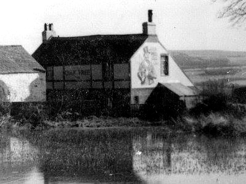 The Oak Tree Inn seen across the flooded field, with its name painted along the side