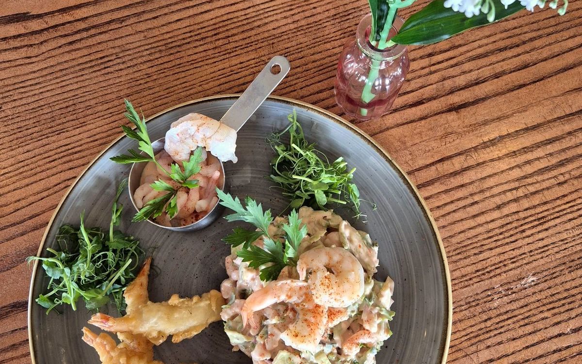 Oily's prawn salad served overhead — prawn cocktail, tempura king prawns and pea shoots on a grey plate